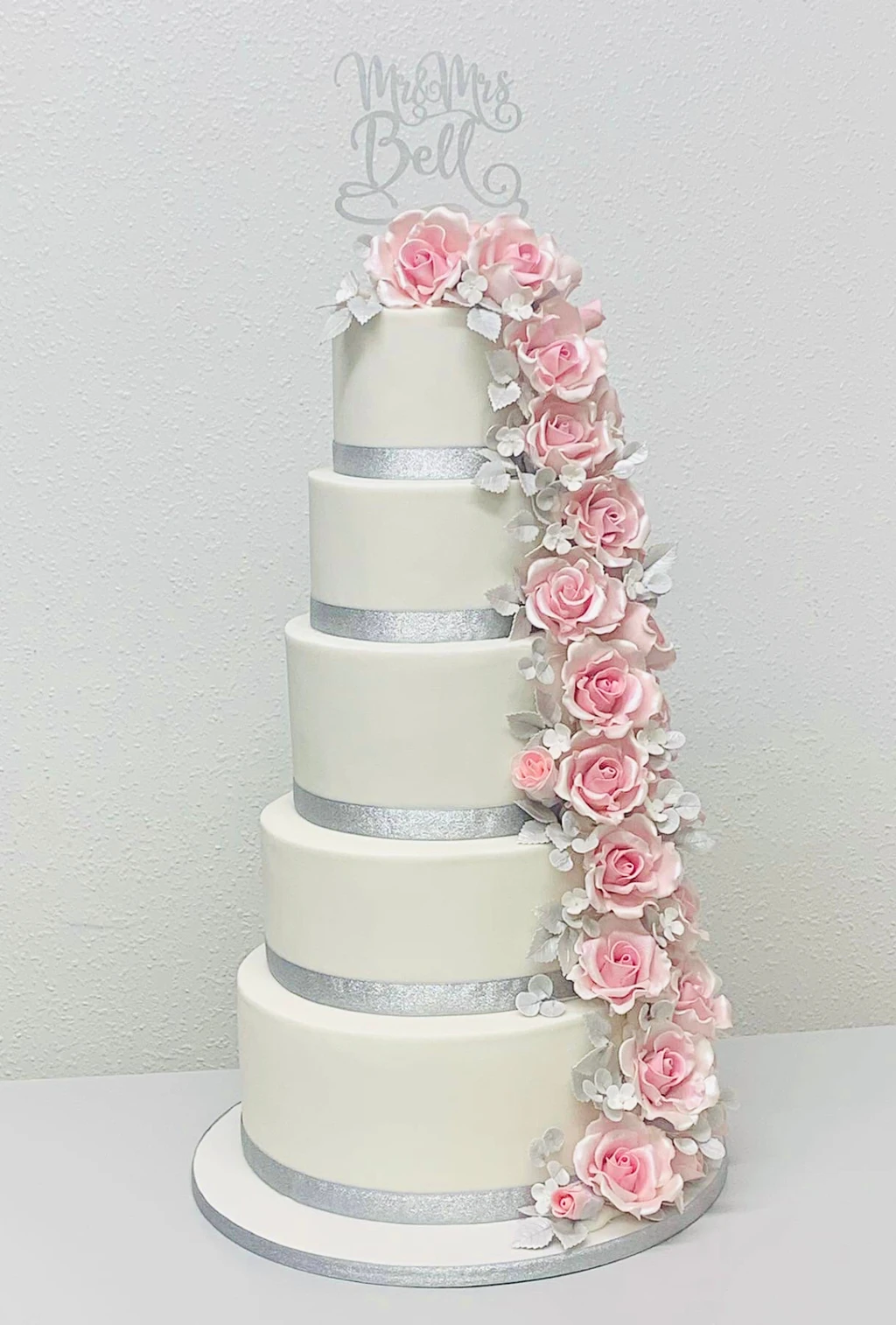 Tall white wedding cake with a cascade of pink roses