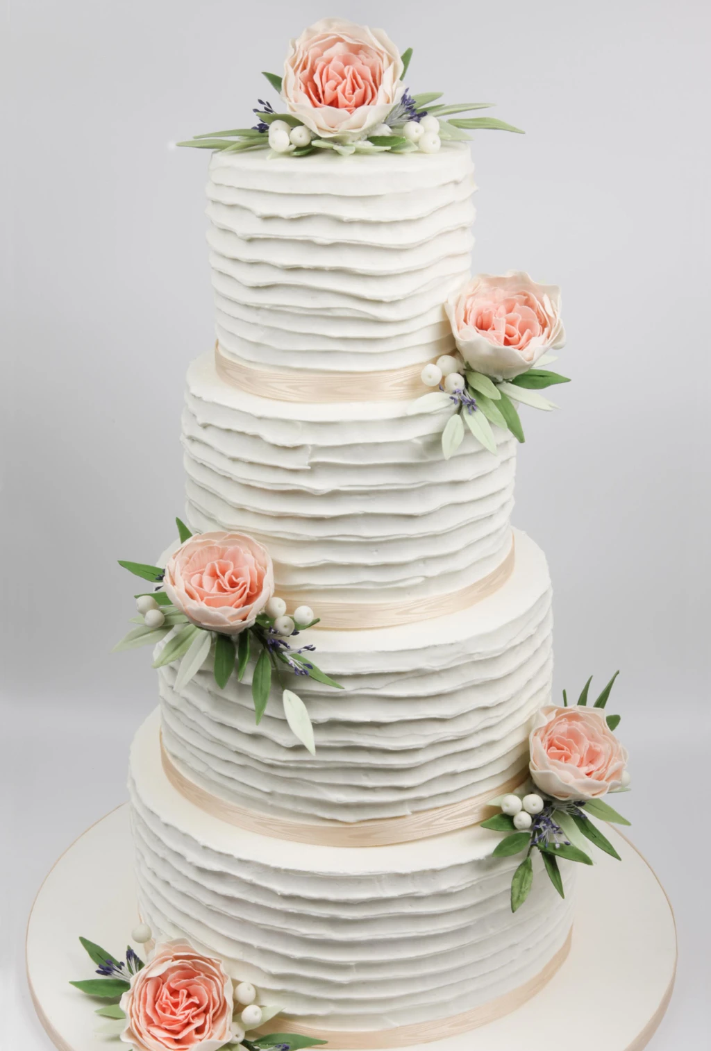 Four-tier white cake with rippled buttercream and peach roses