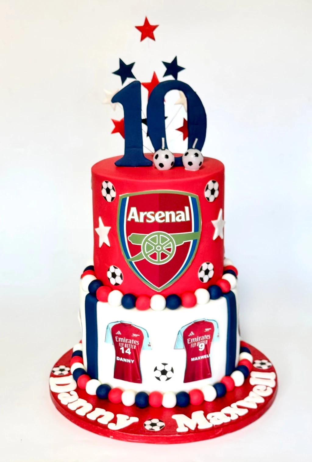 Two-tier Arsenal football cake with shirt decorations and a number ten topper