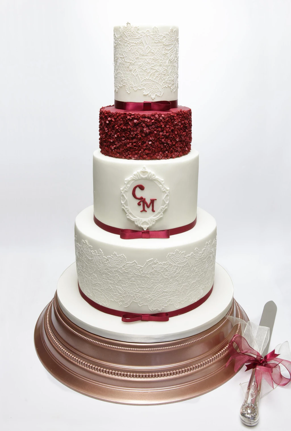 Four-tier white cake with a red glitter tier and red monogram