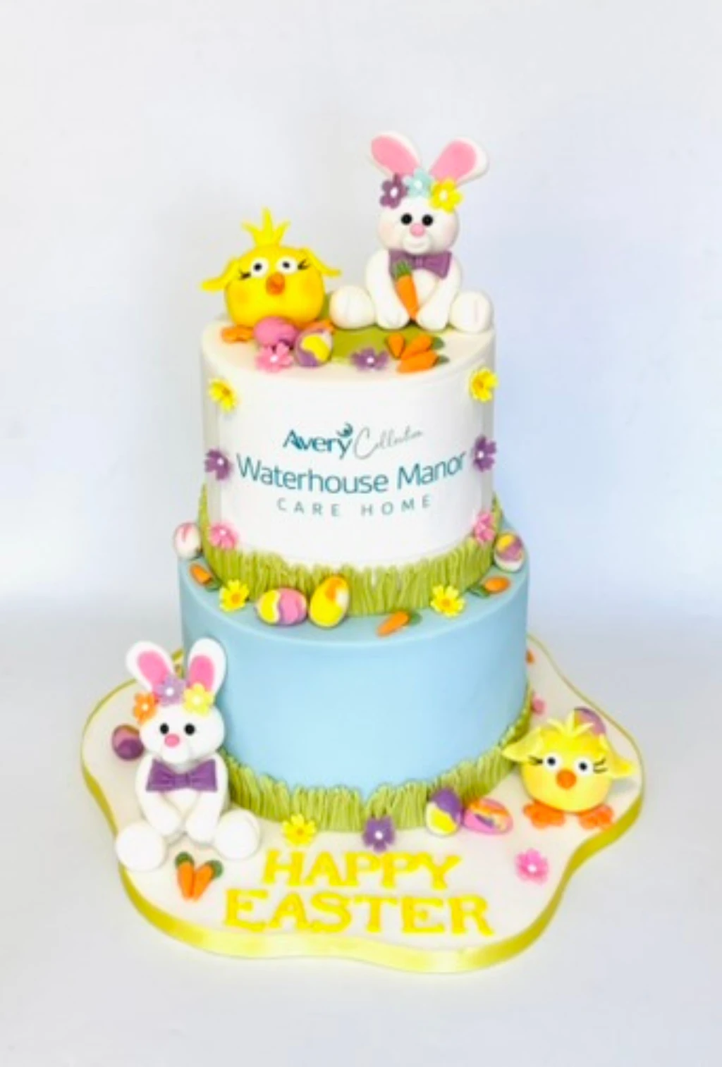 Two-tier Easter cake with rabbit and chick figures, flowers and decorated eggs