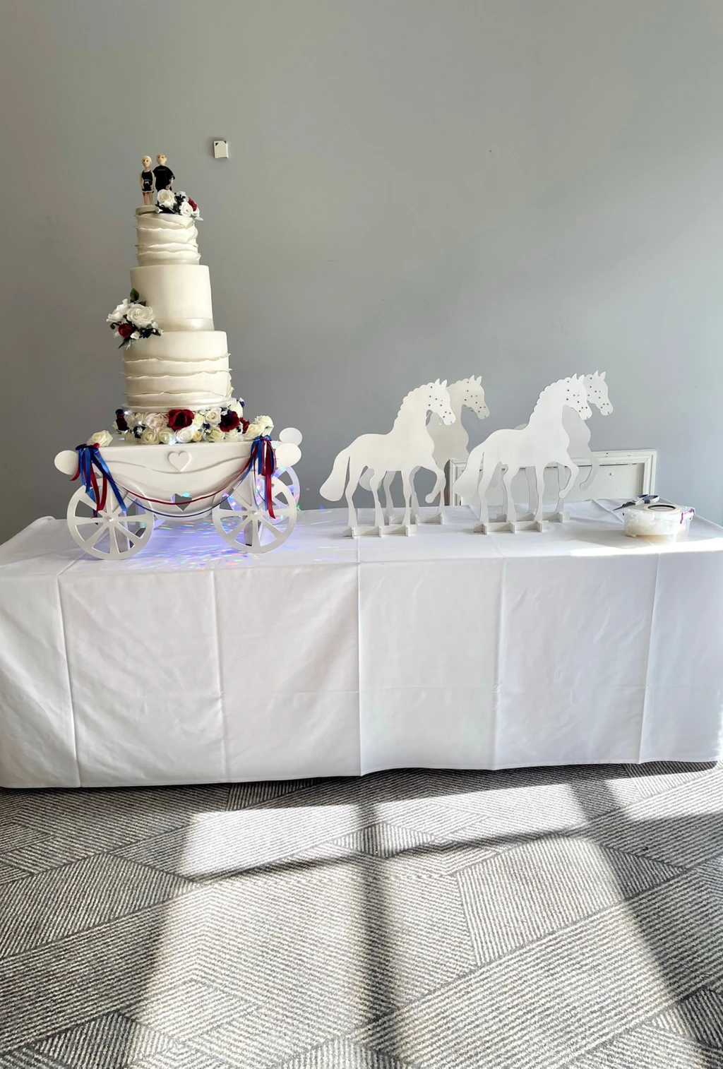 A tall white wedding cake and cupcakes displayed on a table