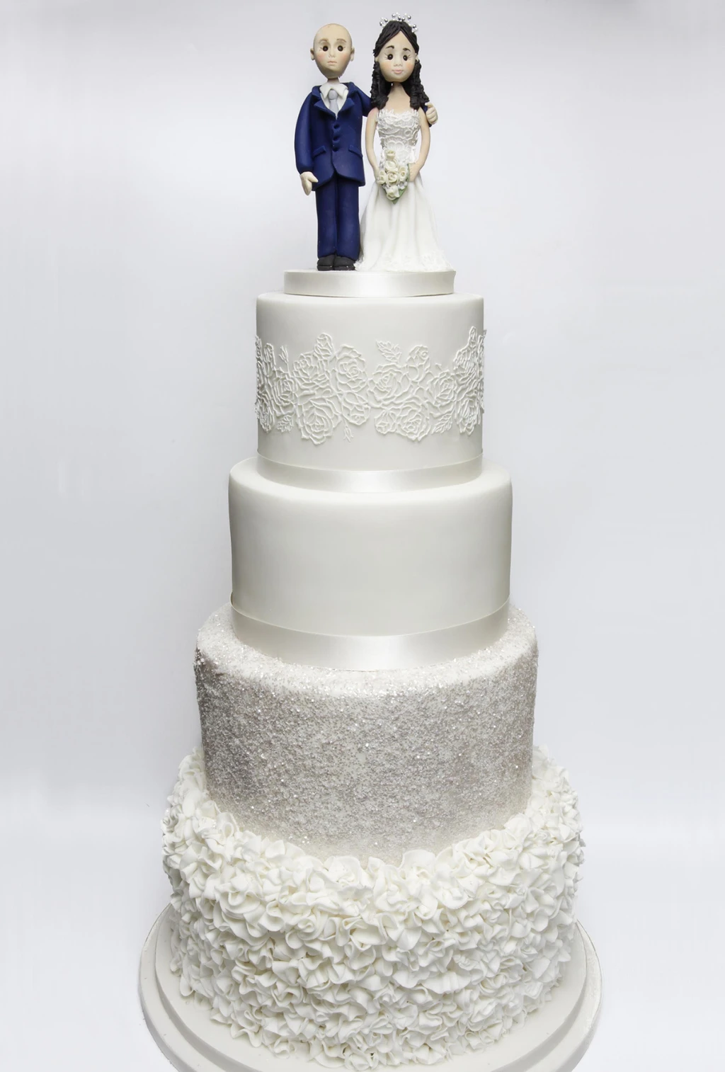 Four-tier white and silver cake with bride and groom figures