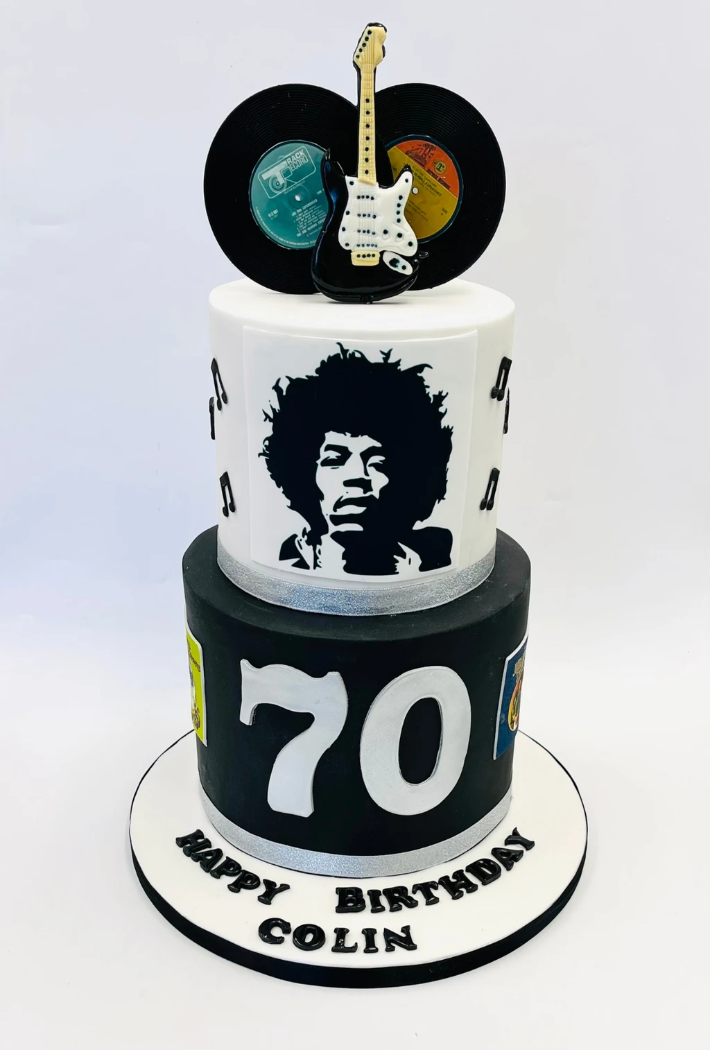 Black and white two-tier 70th birthday cake with a guitarist portrait, records and an electric guitar topper