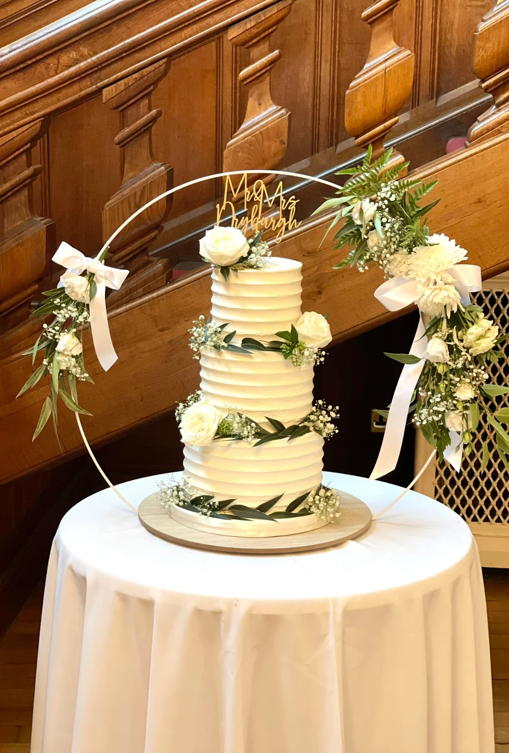 Three-tier buttercream cake with greenery and white flowers