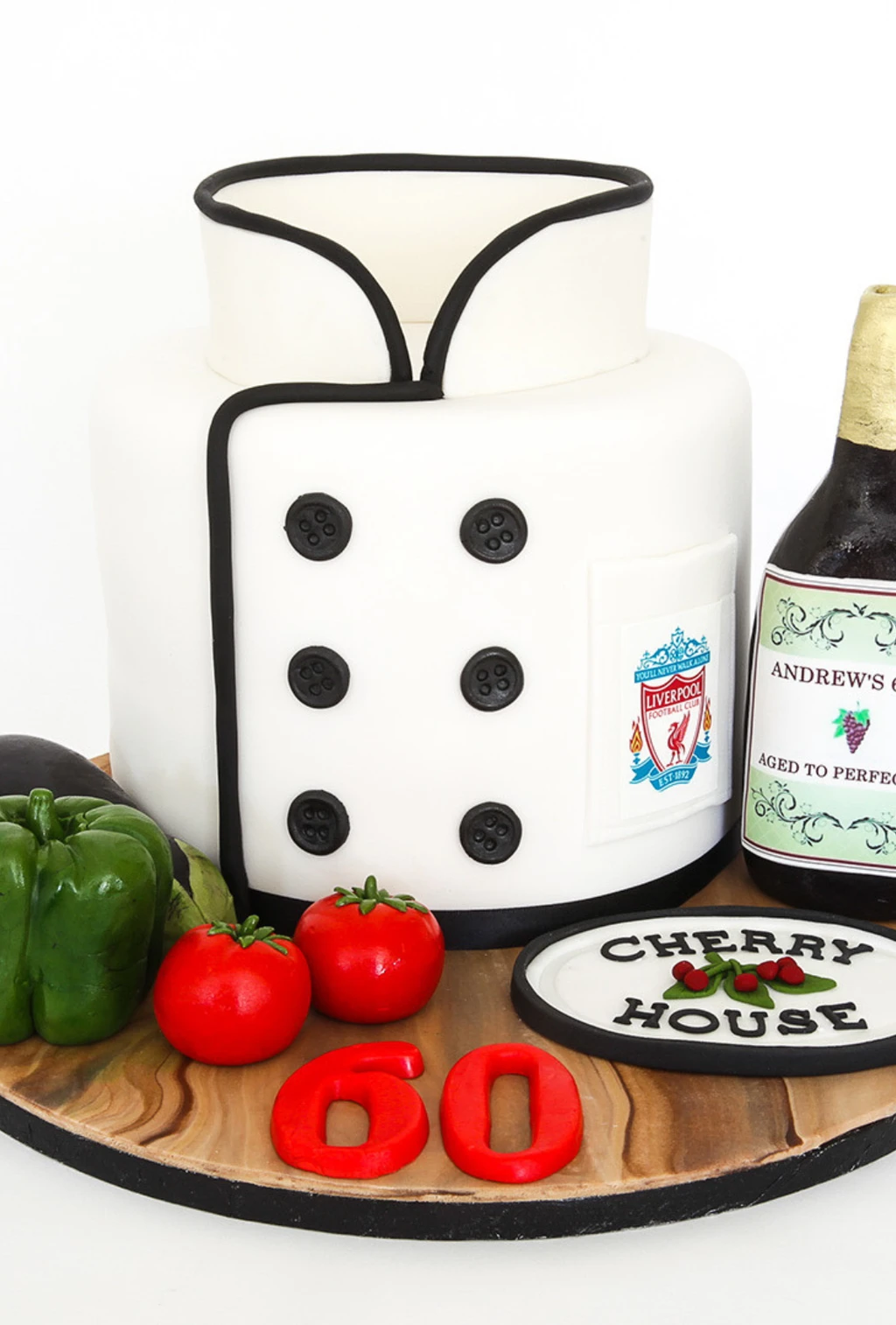 Chef jacket cake with black buttons, a Liverpool crest, vegetables and a wine bottle decoration