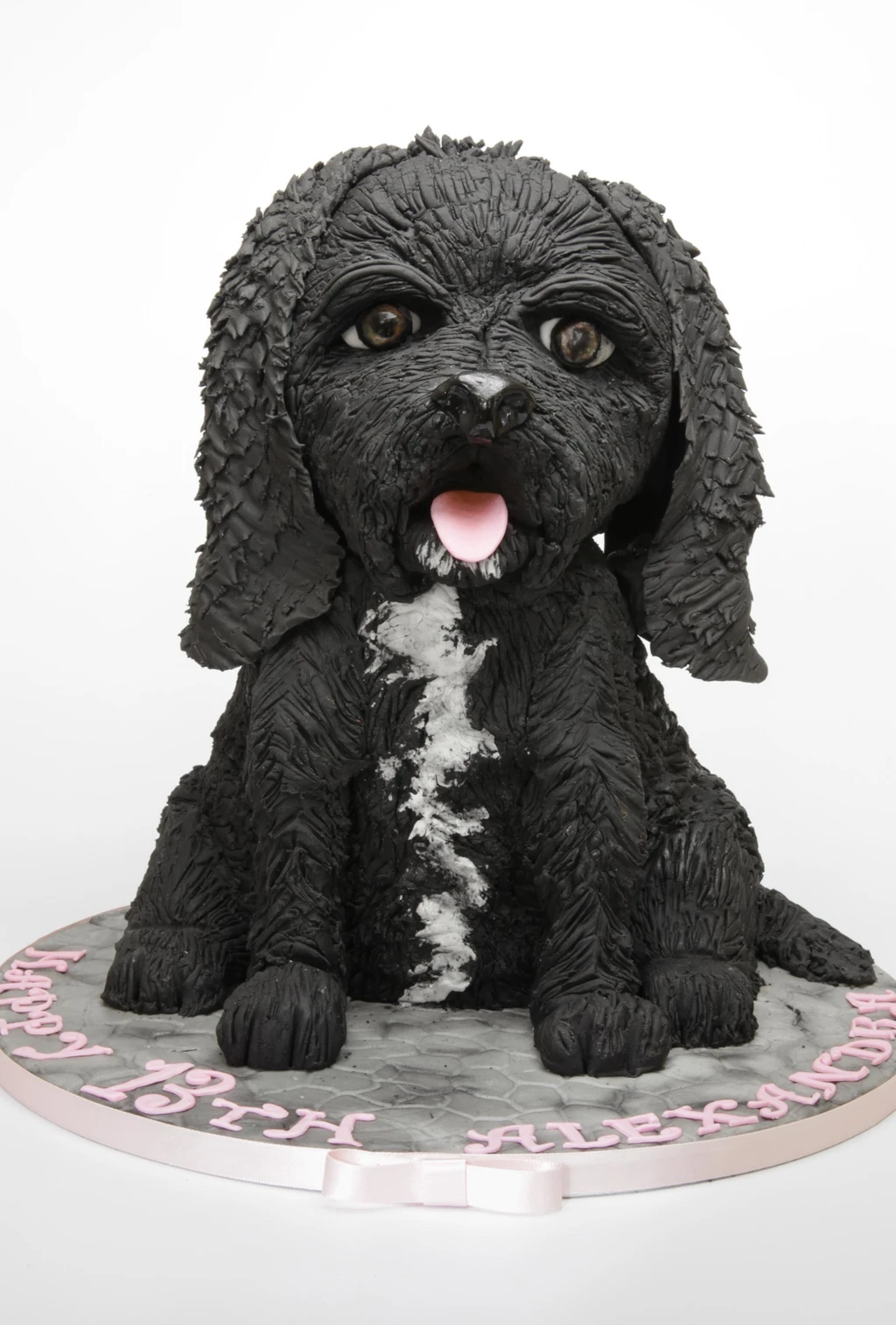 Sculpted black dog cake with textured fur, floppy ears and a pink tongue