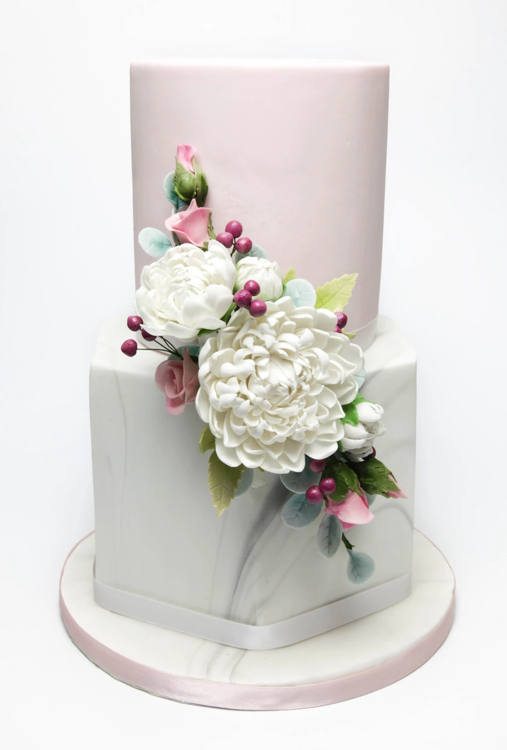 Two-tier pale pink and white cake with white flowers and berry details