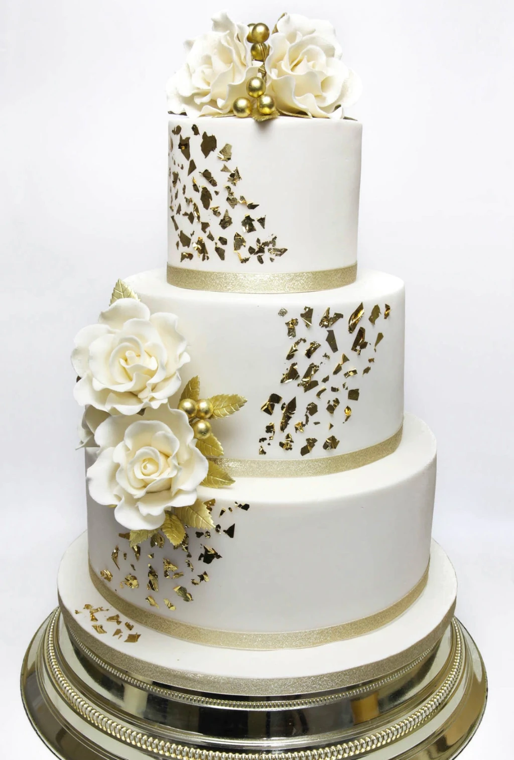 Three-tier white cake with gold leaf details and white flowers