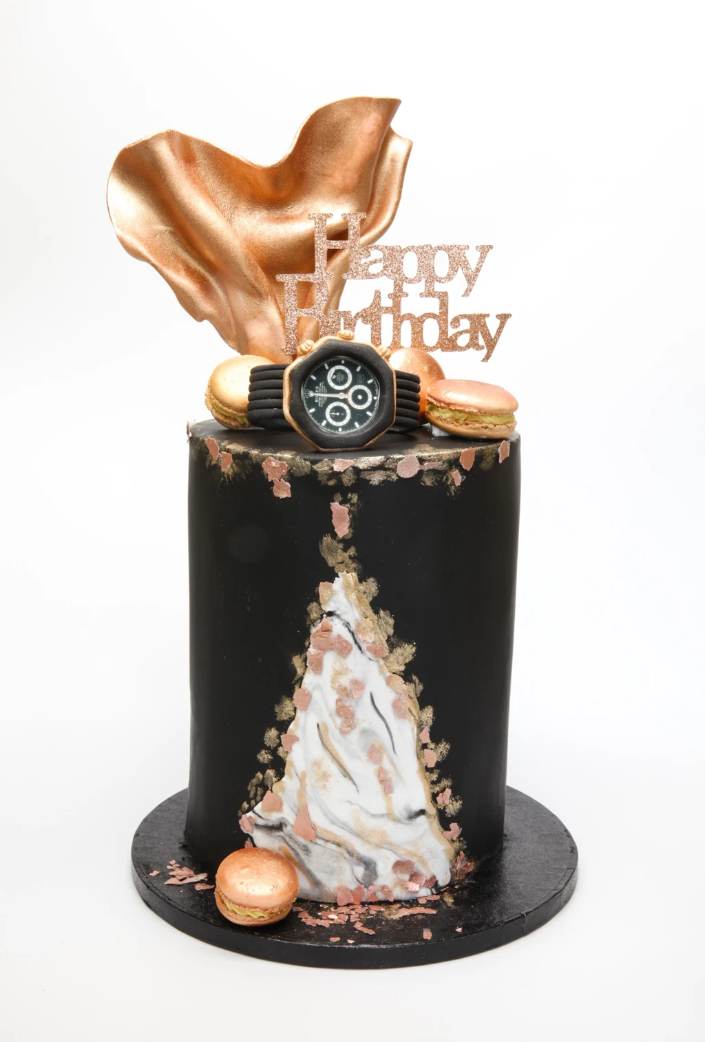 Black birthday cake with a marbled panel, metallic gold decorations, macarons and a watch topper