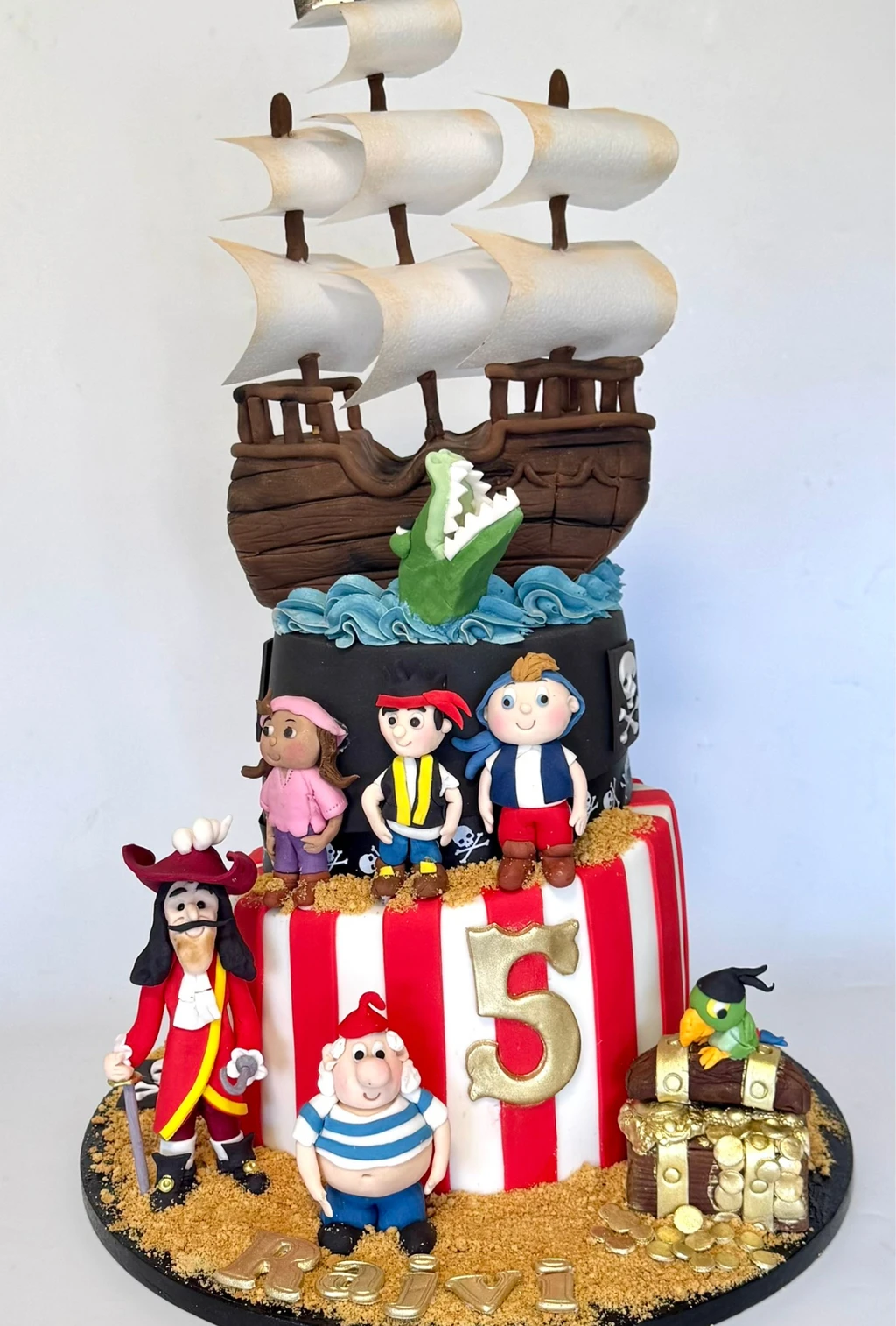 Pirate-themed fifth birthday cake with a sailing ship, figures and treasure chest