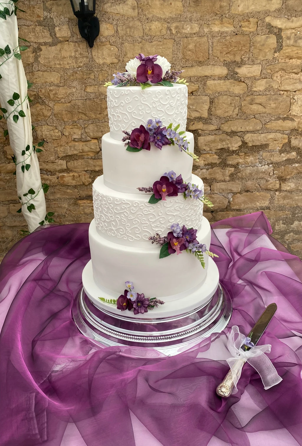 Four-tier white cake with purple flowers