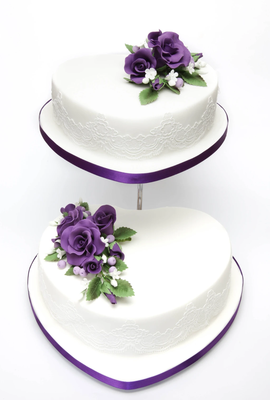 Two white heart-shaped cakes on a stand with purple roses