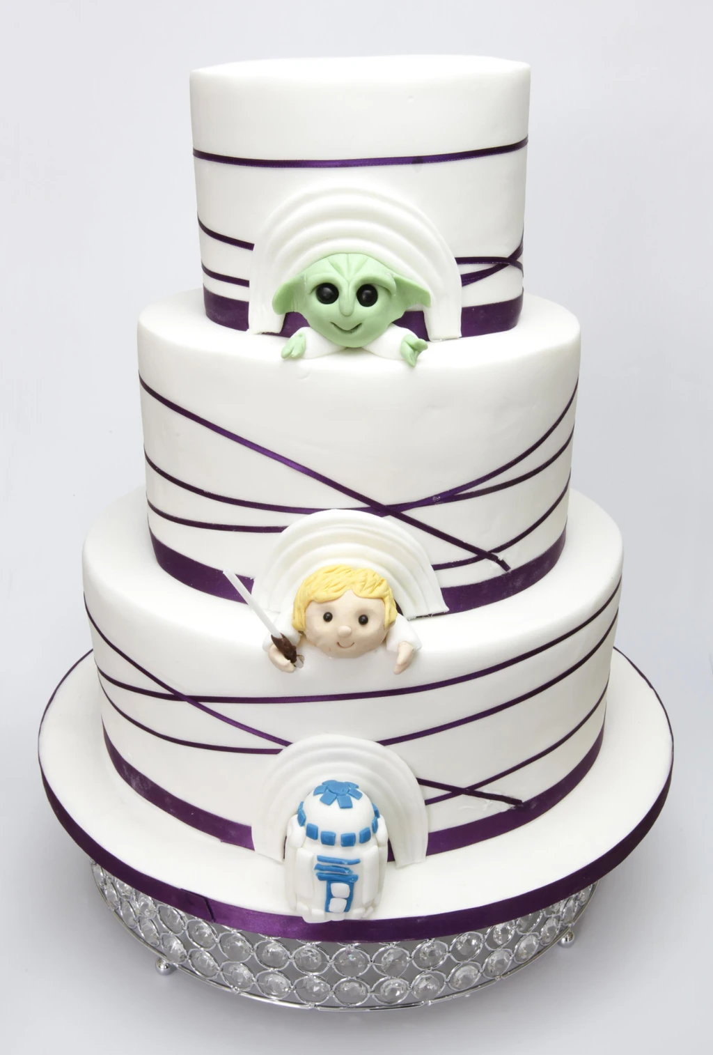 Three-tier white cake with purple ribbons and character decorations