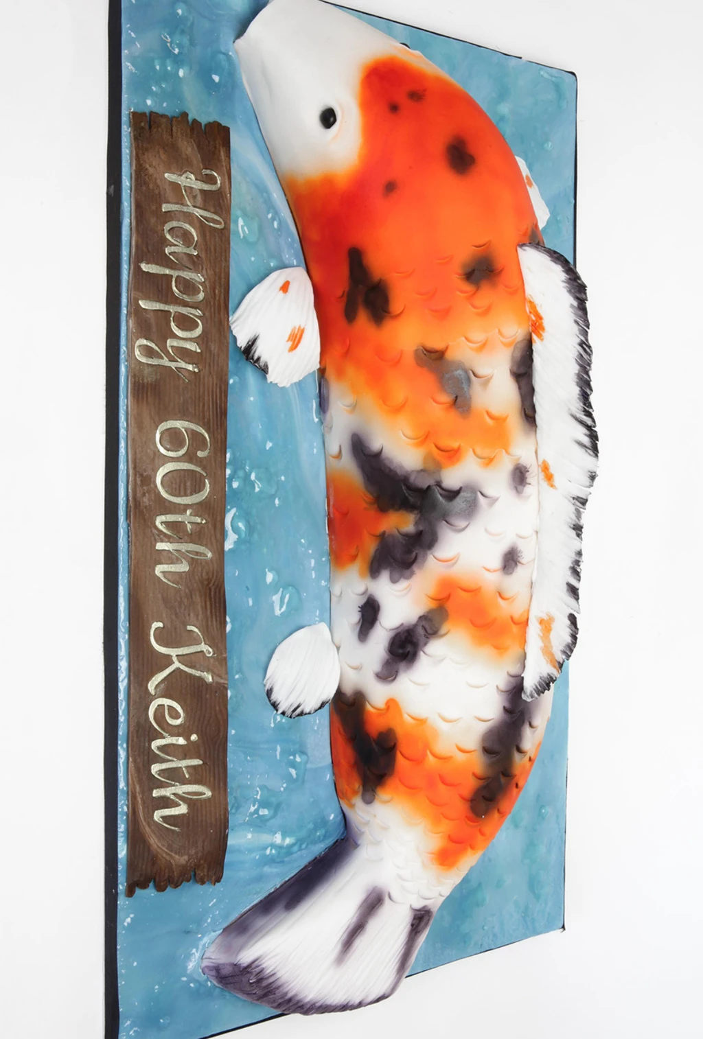 Sculpted orange, white and black koi fish cake on a blue water-effect board