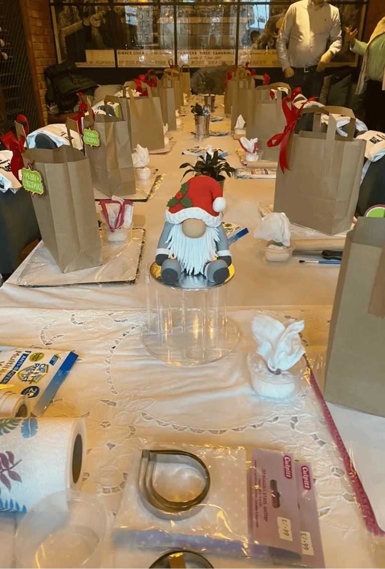 A workshop table with icing tools, aprons and a decorated cake