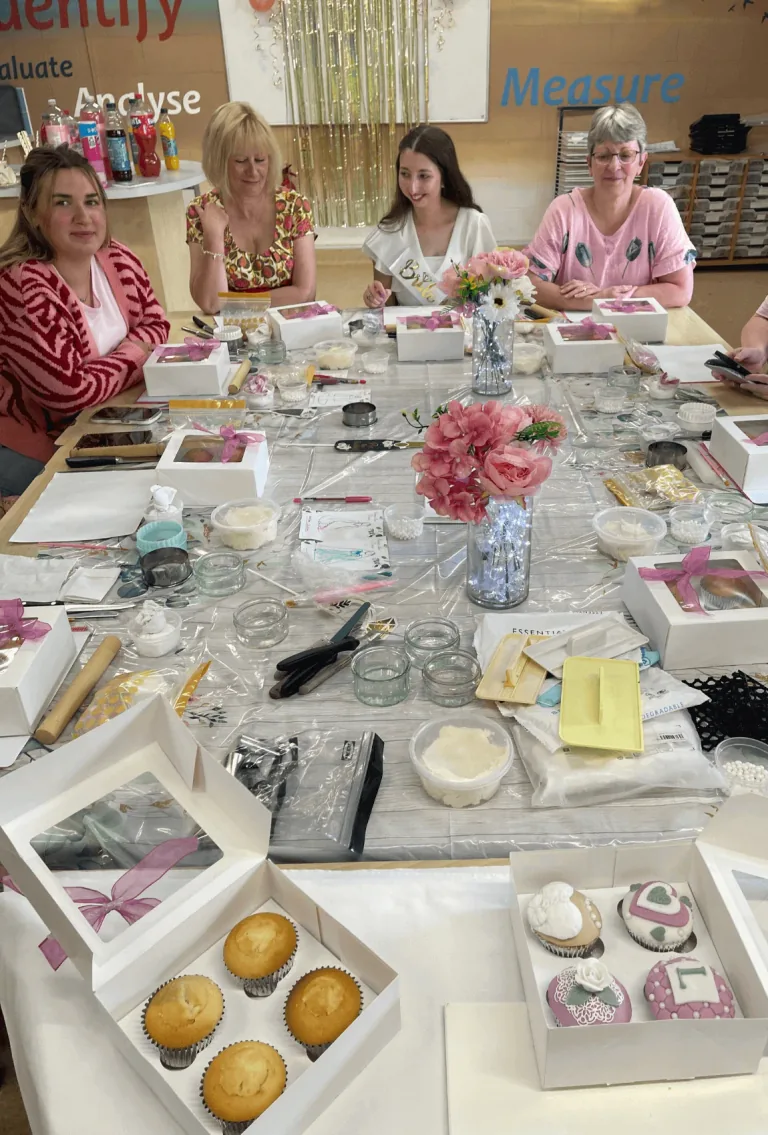 Participants decorating cupcakes around a table set with icing tools
